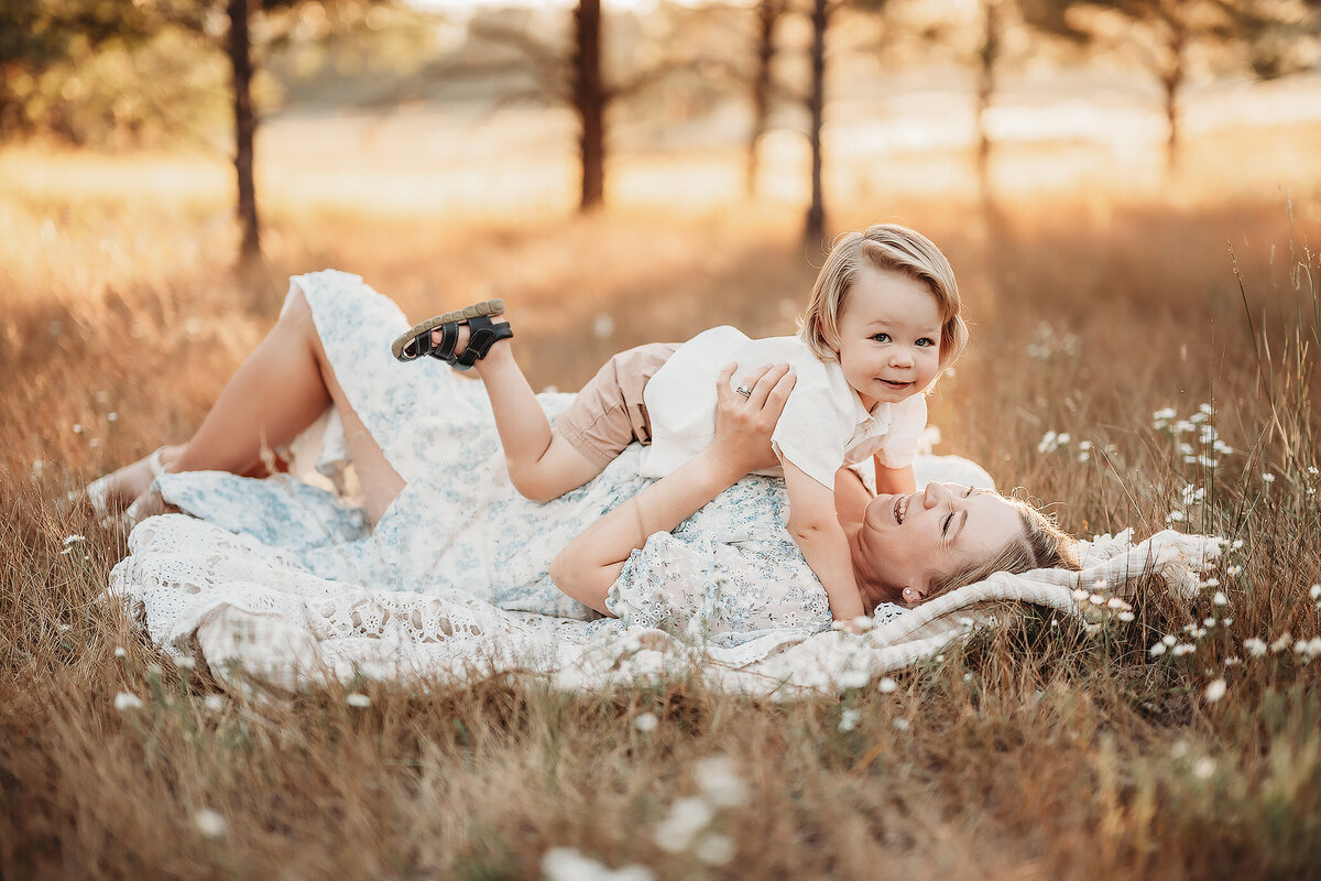 boy laying on mom in the grass