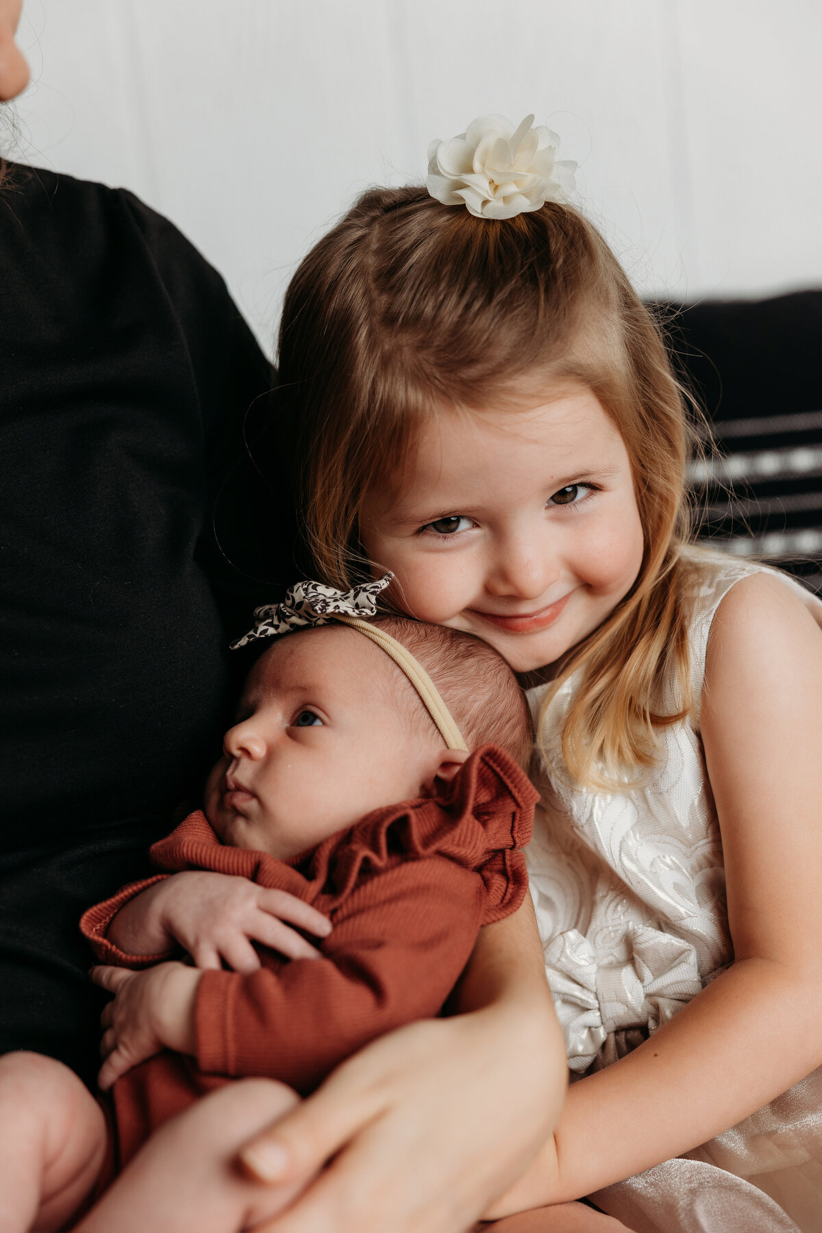 big sister smiling at the camera hugging her little sister