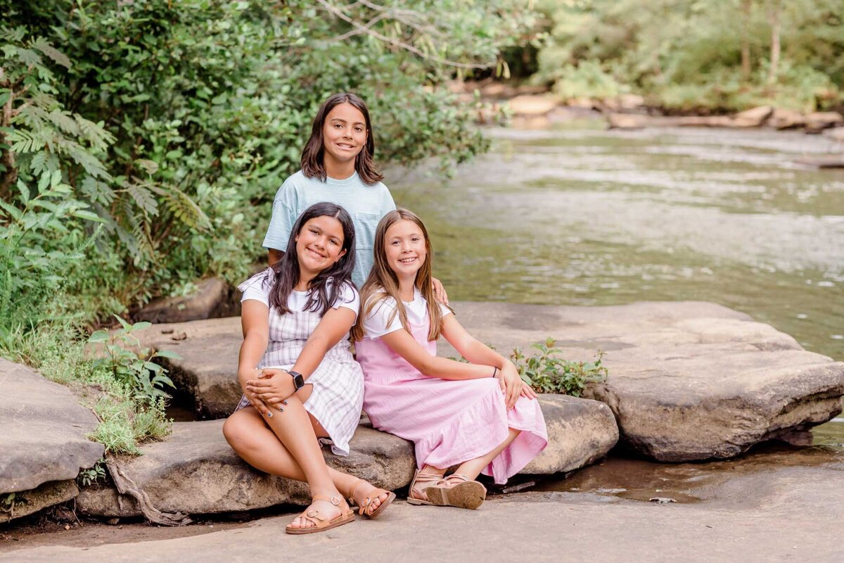 Siblings sitting on a rock beside a creek in Peachtree City, Georgia.