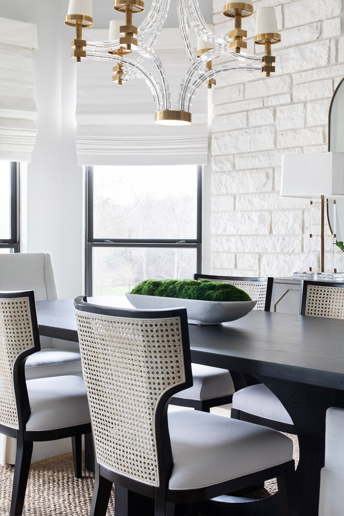 dining room with white brick wall, black table and chandelier