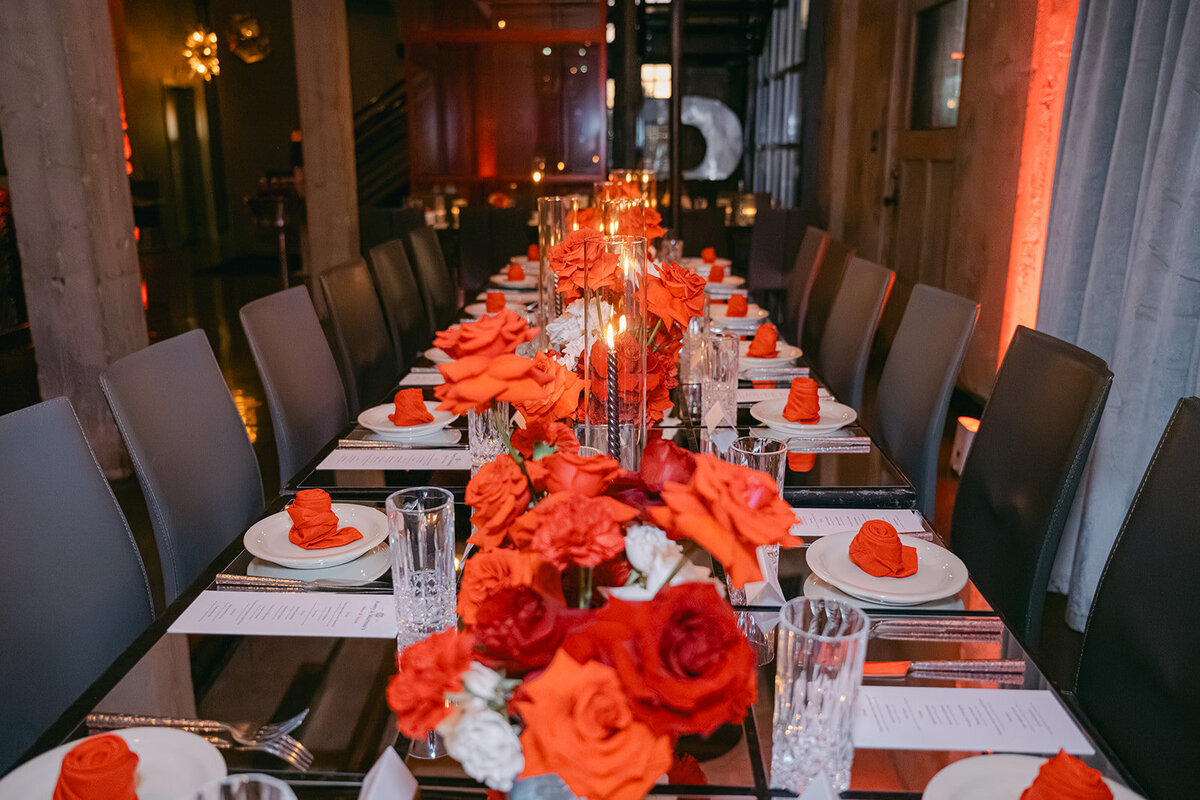 Overhead view of editorial tablescape with vibrant red floral arrangements and luxury accents