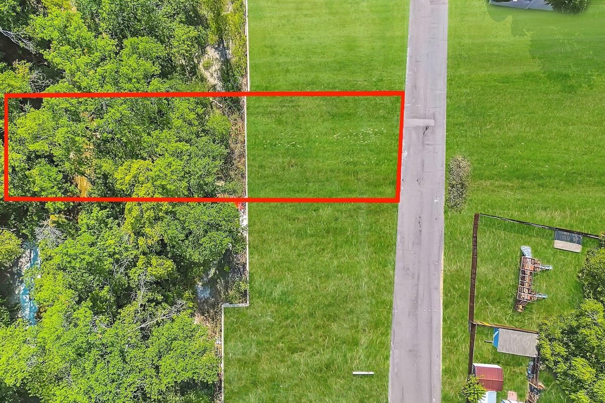 Vacant lot bordered by lush greenery, offering a peaceful backdrop for a future custom home in a highly desirable neighborhood.