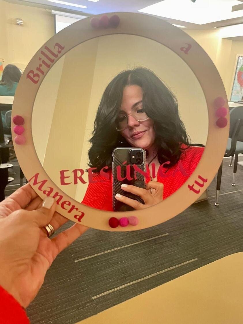 The essence of candid moments as a woman in a red t-shirt takes a mirror selfie with her cellphone during the art workshop.