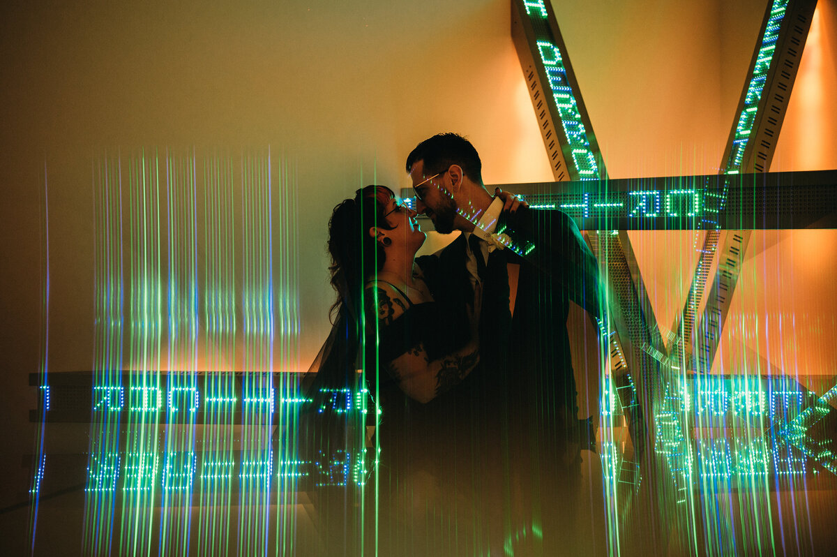 Bride and groom get close in front of an art installation in Art Museumm in Akron.