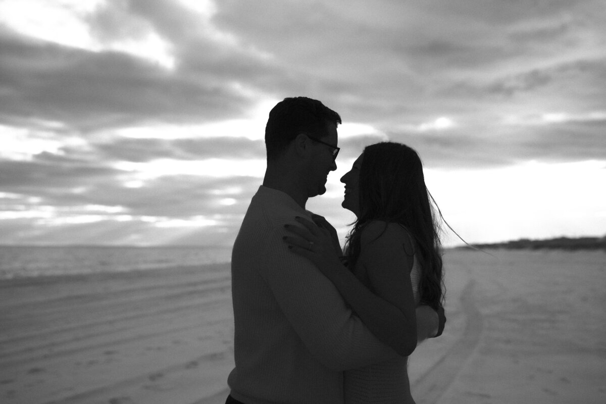 Silhouette of young couple against sand and sunlit skies.
