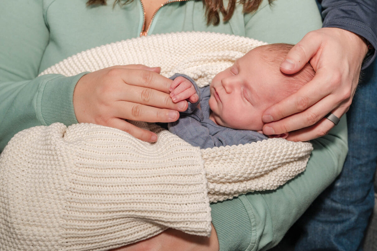 Newborn with mom and dad's hand in the frame