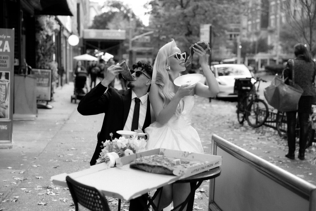 Bride and groom toasting their pizza slices together in celebration of their NYC elopement.