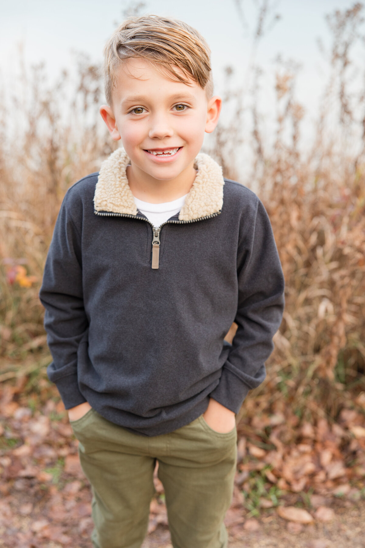 A little boy with his hands in his pockets and smiling