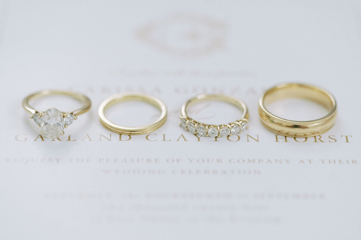 wedding rings sitting on top of a wedding invitation