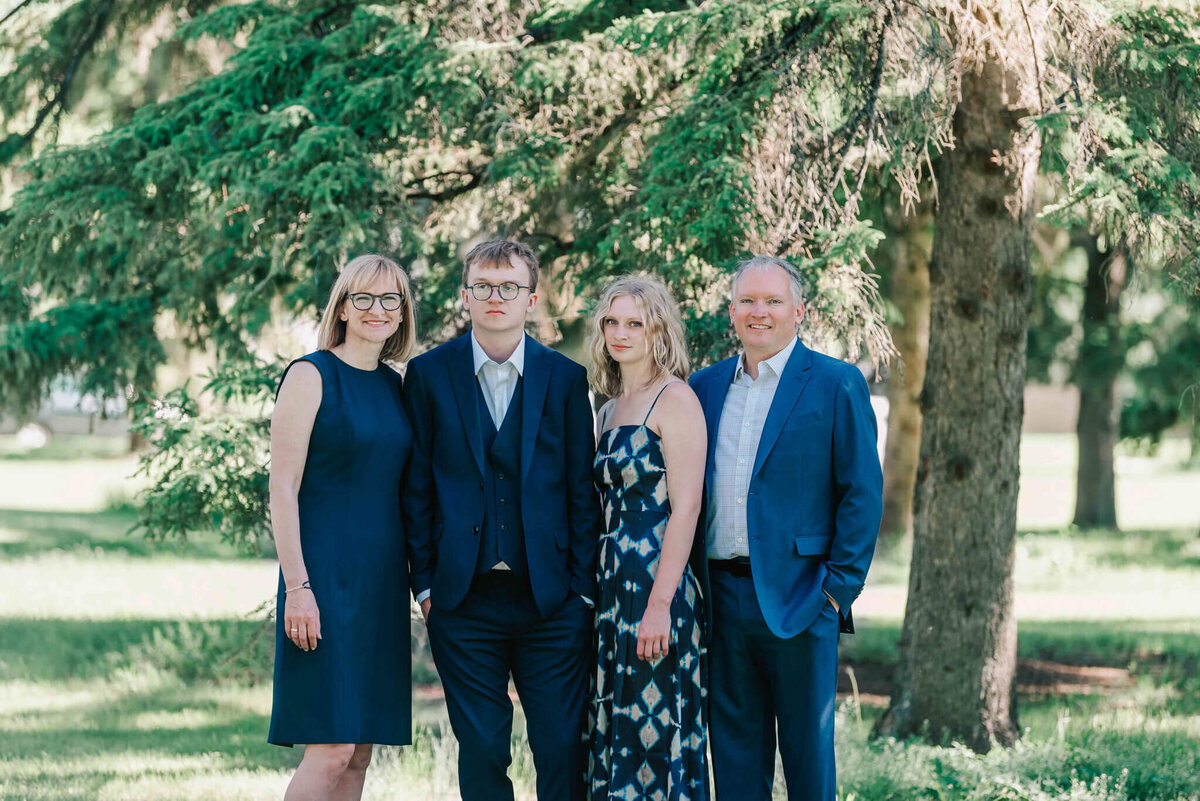 Standing in front of a large tree with the whole family. 