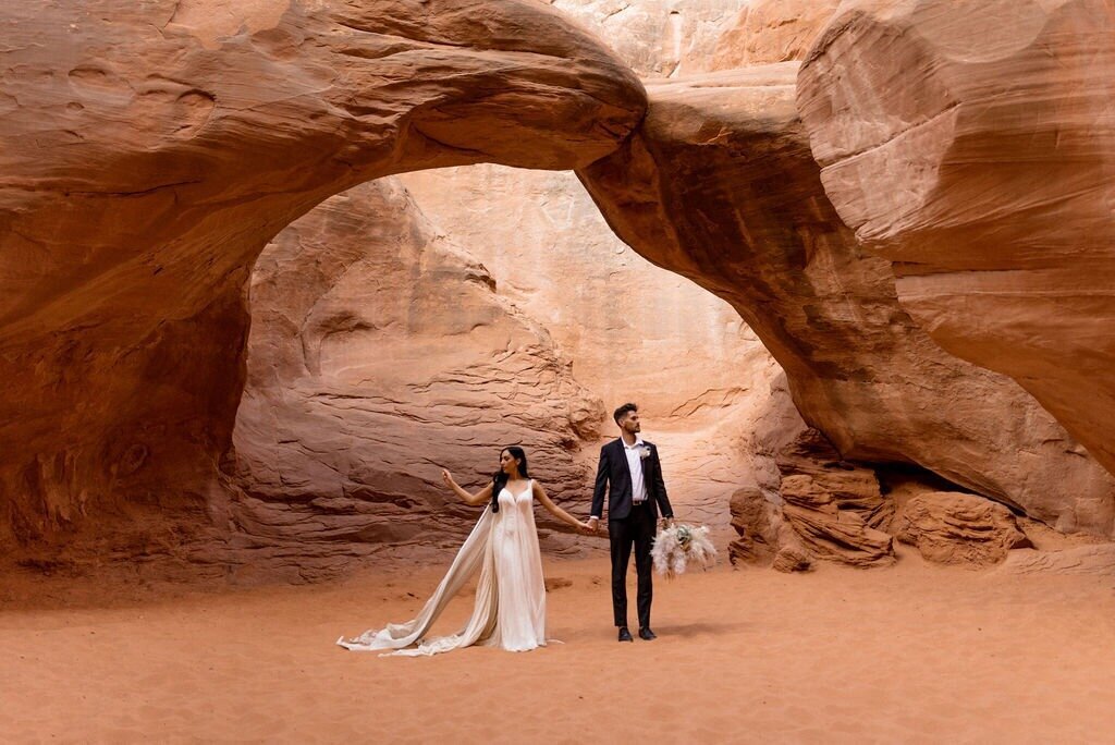 Couple in wedding attire just married under the red arches in moab
