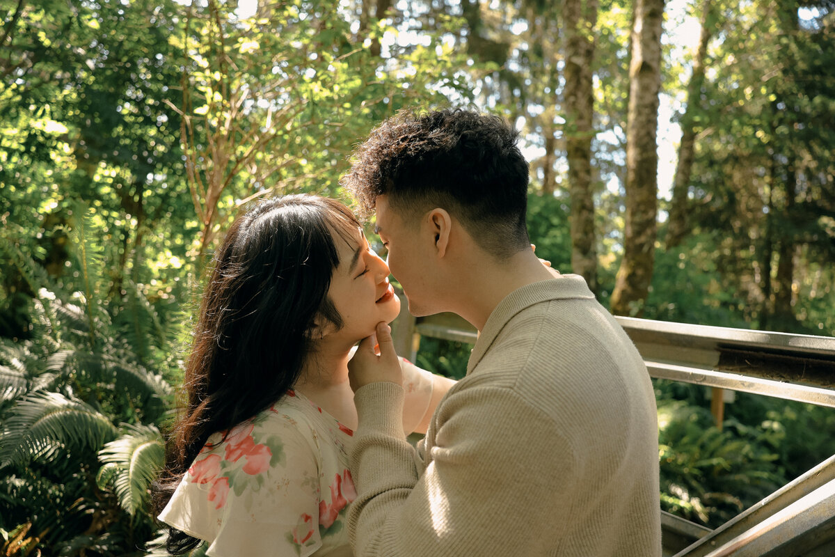 Romantic Forest Engagement Session with Couple Kissing Under Sunlight