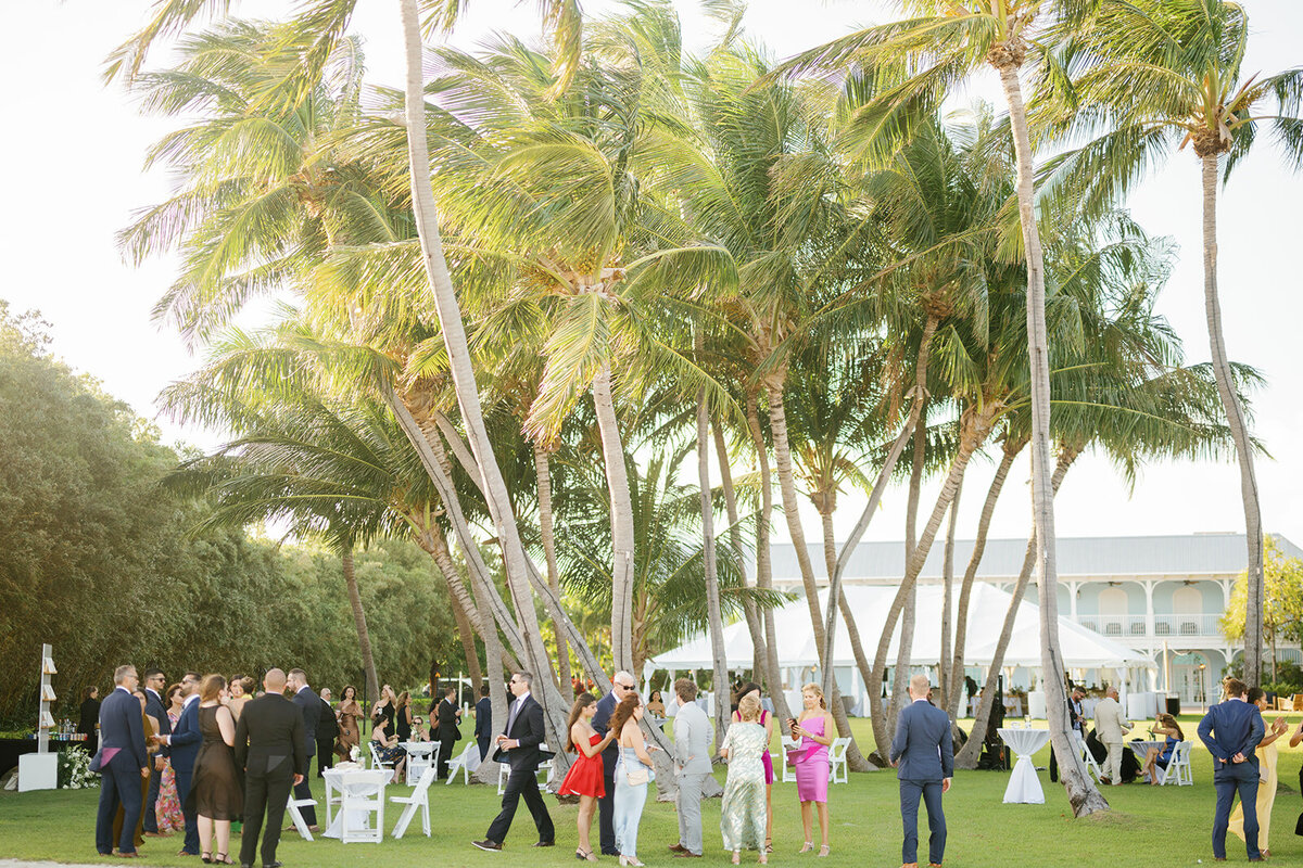 A relaxed cocktail hour scene with elegantly dressed guests sipping drinks and chatting under the warm Florida sun at Stephanie and Bradley’s Islamorada wedding. Photographed by Claudia Amalia Photography.