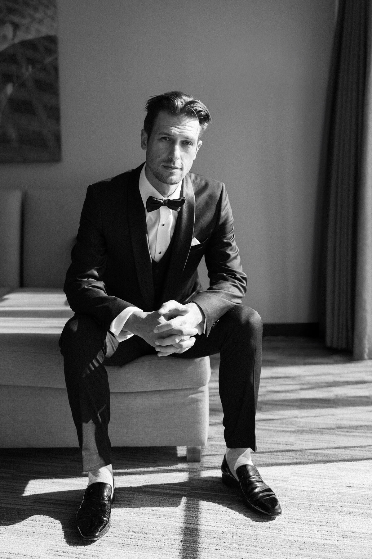 Groom portrait at the Highlands in Detroit. He is sitting on a stool next to the city scape. 