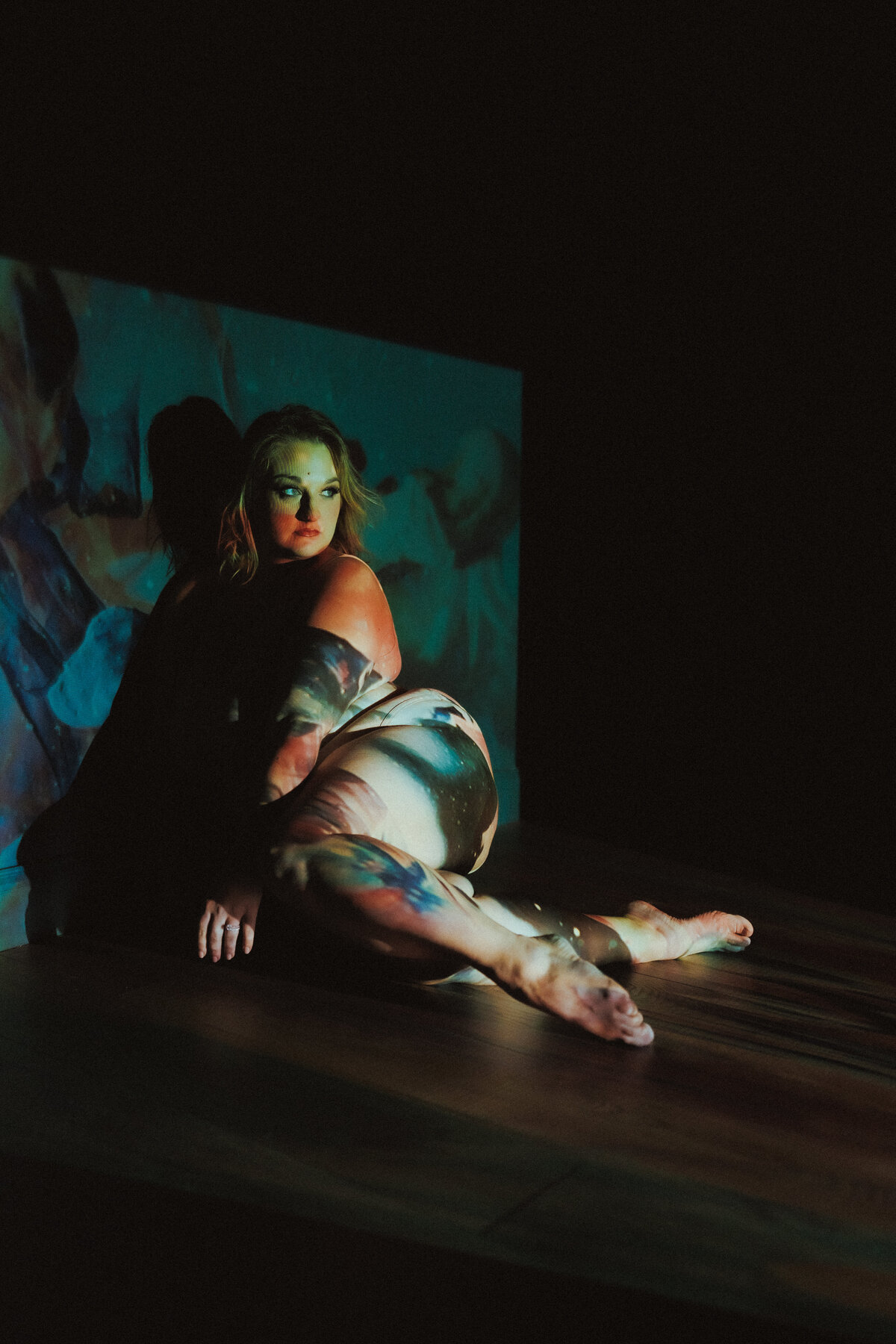 Lying against a dark wall with starry visuals projected across her body, this portrait fuses boudoir and visual art
