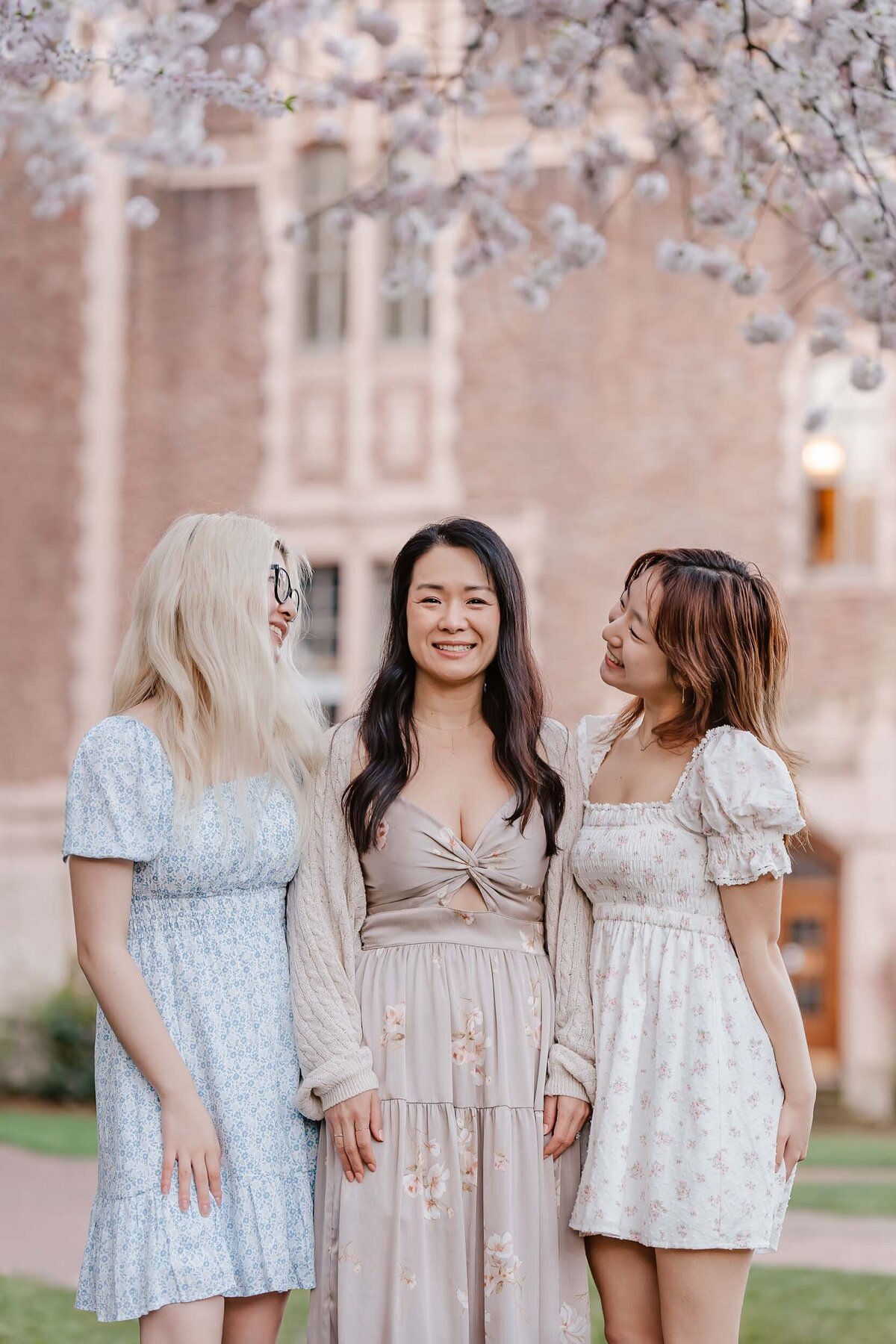 Sisters gazing at their mother under blooming cherry blossoms at the University of Washington, full of springtime warmth.