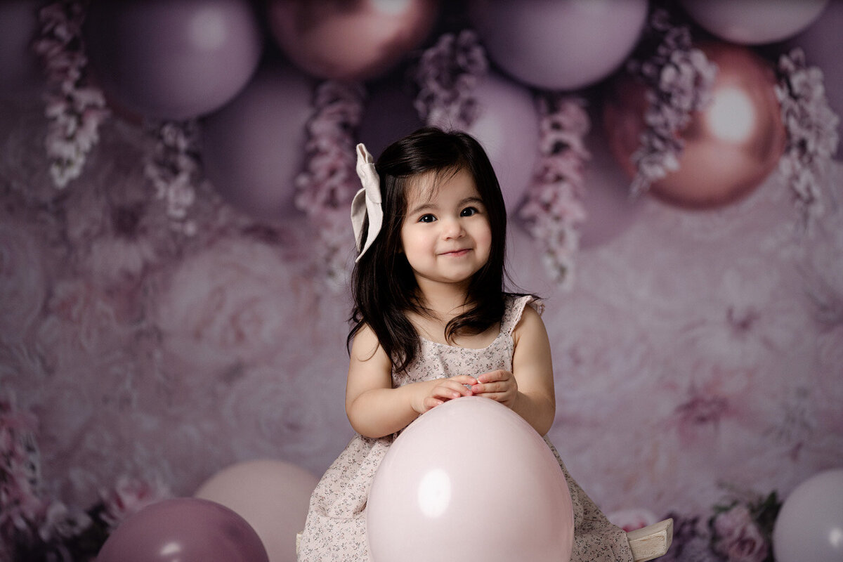 Birthday girl turns one holding balloon by for the love of photography lansing