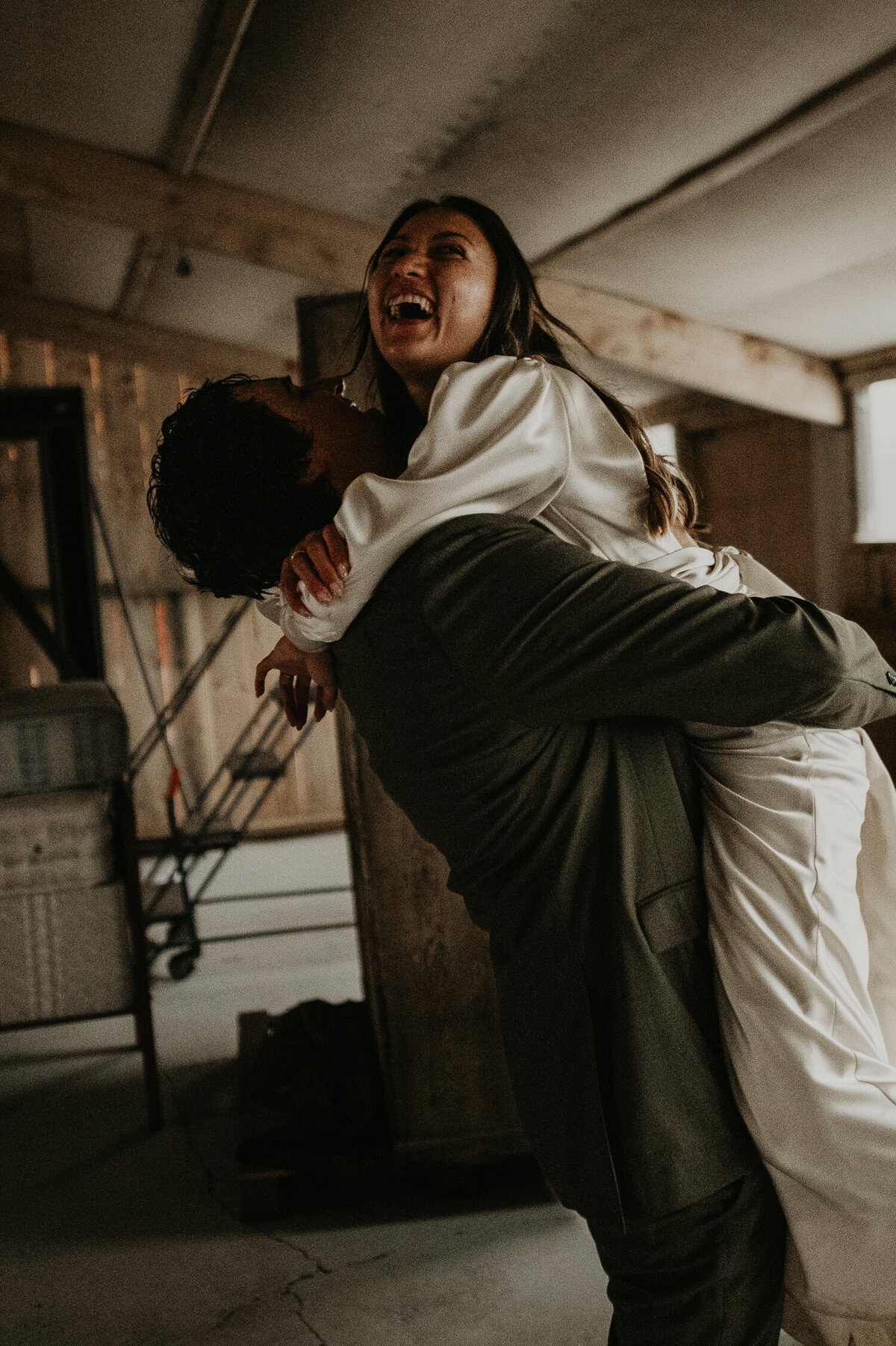 A Groom spins his bride around has he picks her up.