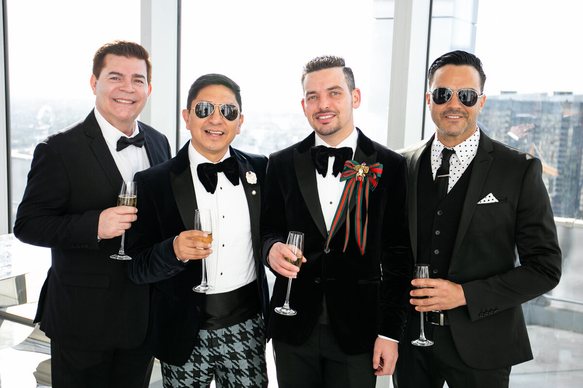 A group of wedding guests in tuxes smiling