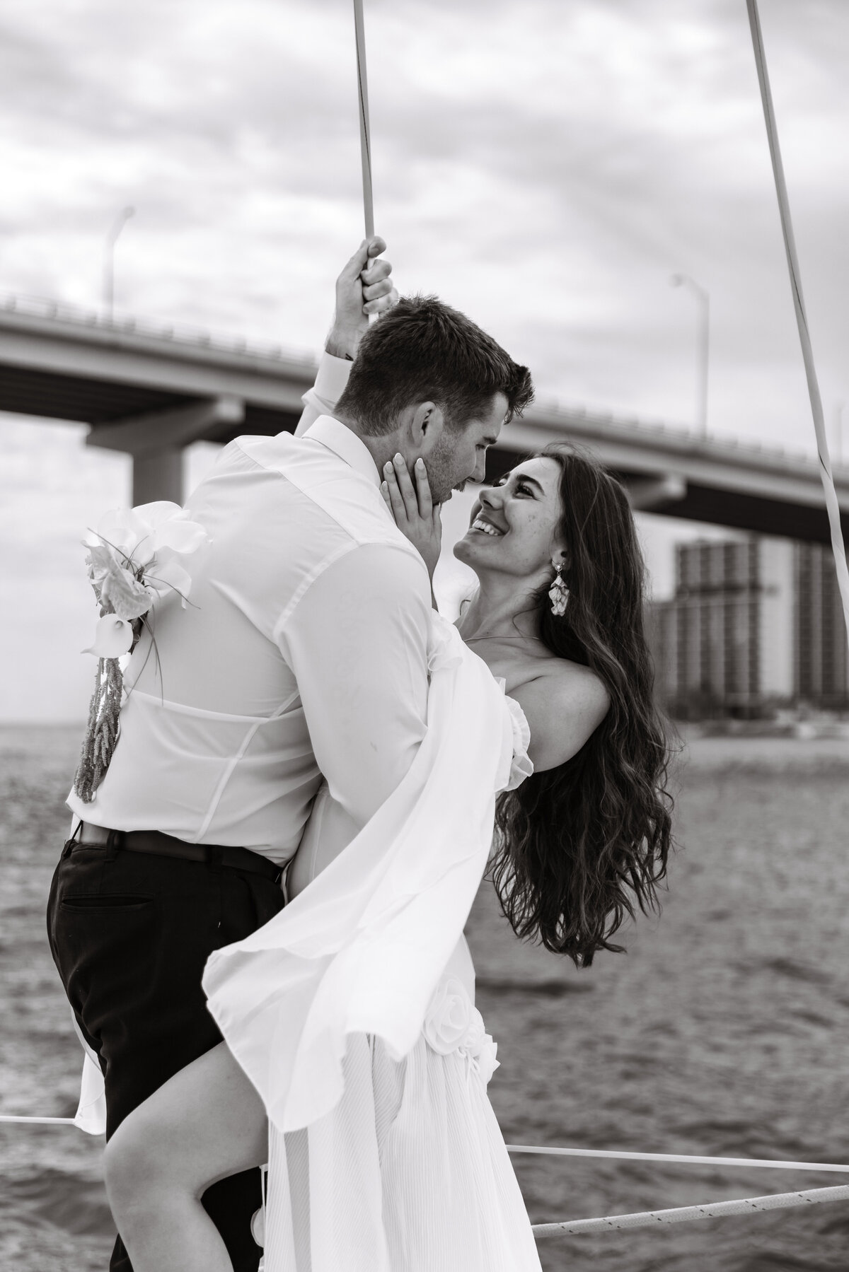 Shannon Lee, from Love Like Wild Photography, captures a playful, romantic moment as a couple shares a kiss by the waterfront.