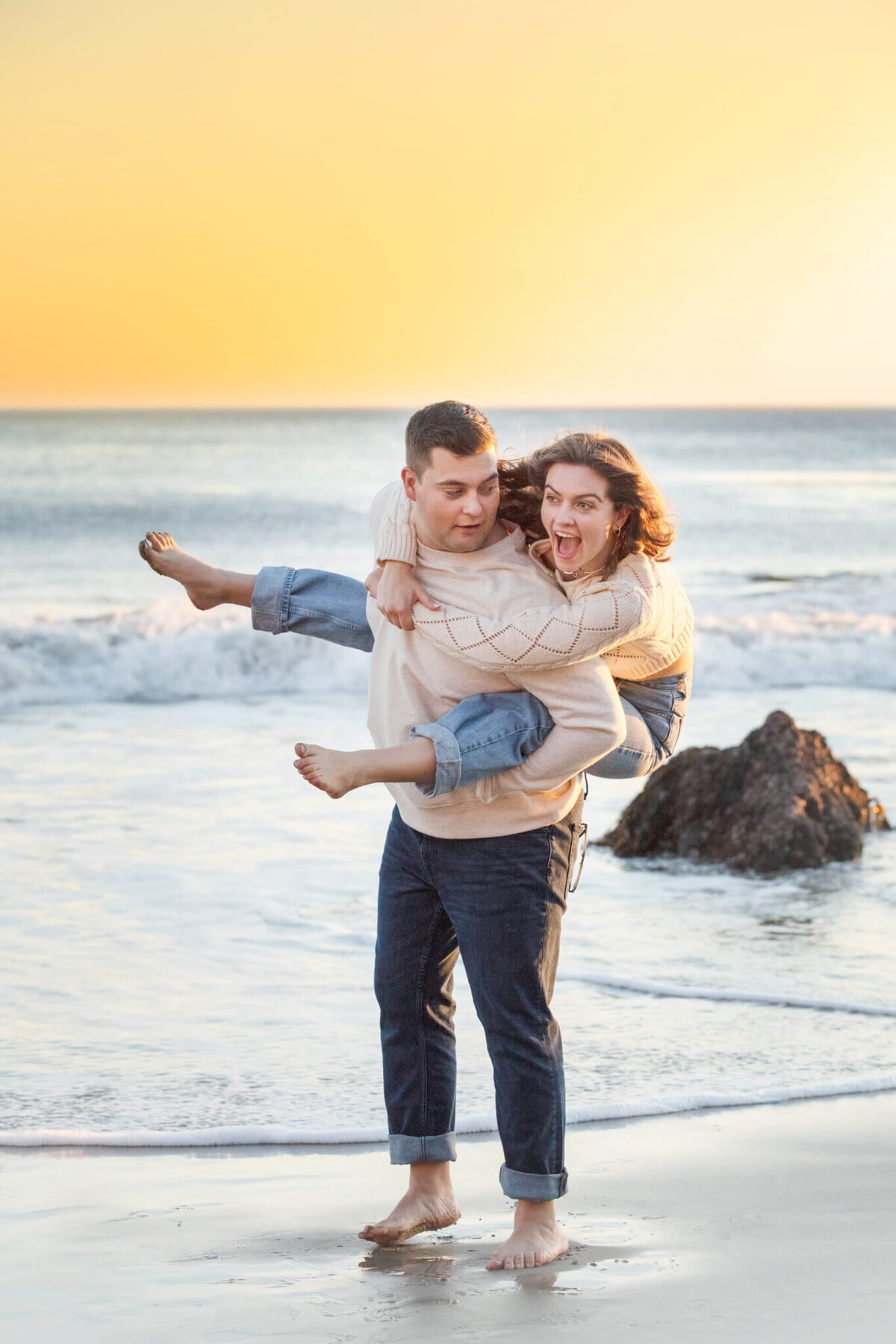 Teen brother and sister laughing at the beach in Malibu while the sun sets captured by Los Angeles Photographer