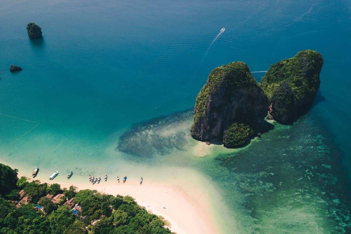 Private superyacht anchored near a secluded white sand beach in the Phi Phi Islands, Thailand.