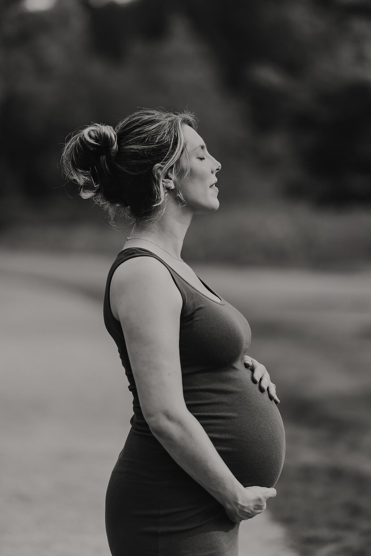 Beautiful pregnant mother gently holding her belly with eyes closed, embracing a peaceful and reflective moment.