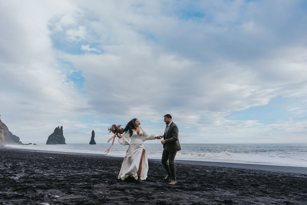 Husband and wife dance on the shores of the Black Sand Beach in Iceland 