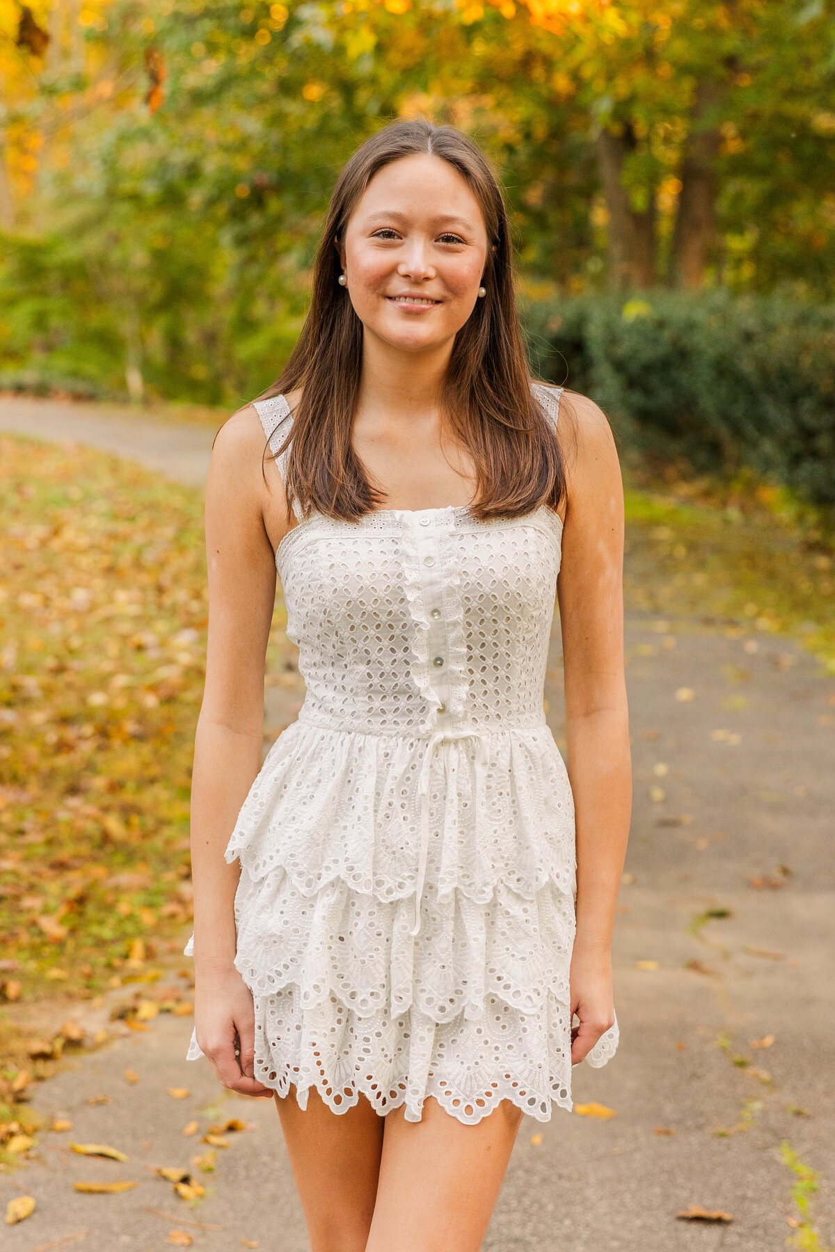 senior girl standing ankles crosses in the middle of a park path during portrait session