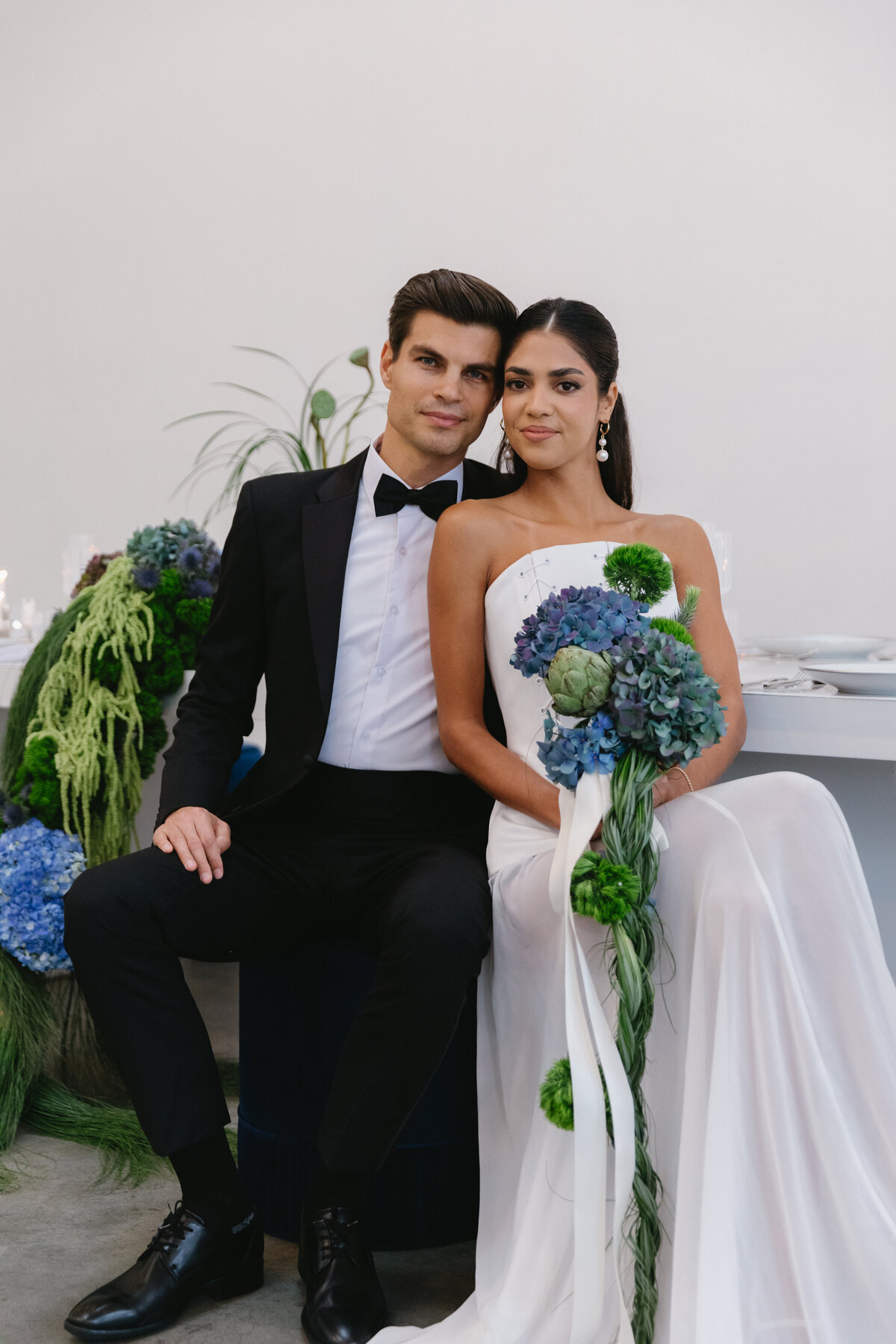 Groom dipping bride in a playful, romantic pose along a minimalist white aisle with draped fabric during an NYC editorial wedding shoot.