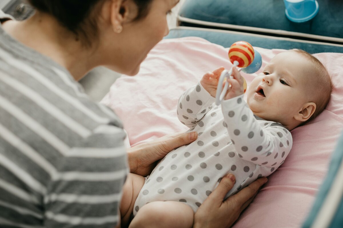 picture of baby lying on back holding a toy
