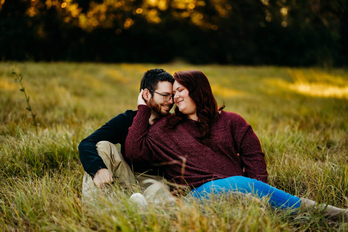 candid engagement photo of couple cuddling in field in lafayette, la