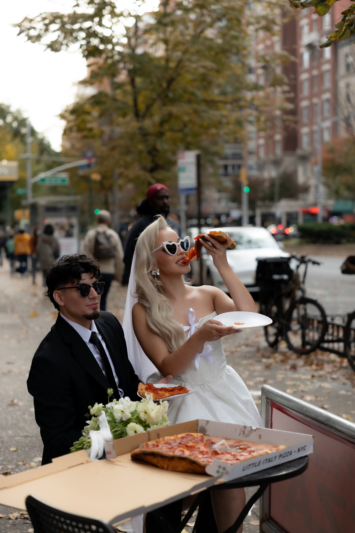 Bride and groom toasting their pizza slices together in celebration of their NYC elopement.