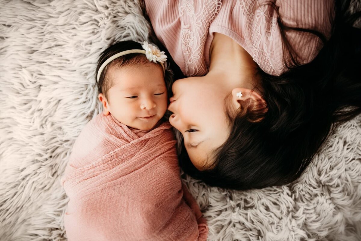 big sister kisses newborn baby sister in an overhead shot