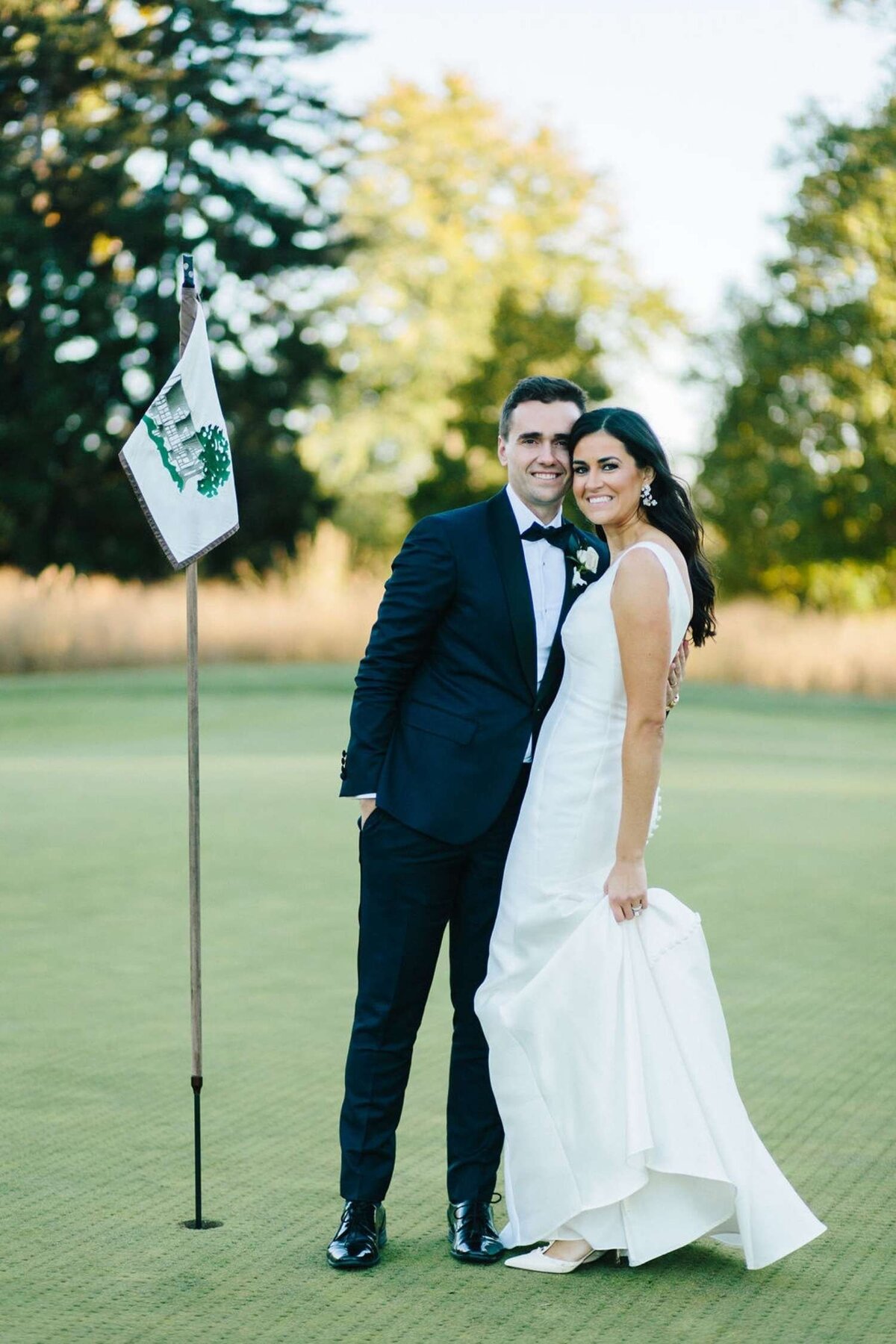 Classic and Elegant Bride and Groom take Portraits  at the 18th Hole on a Luxury Michigan Lakefront Golf Club Wedding.