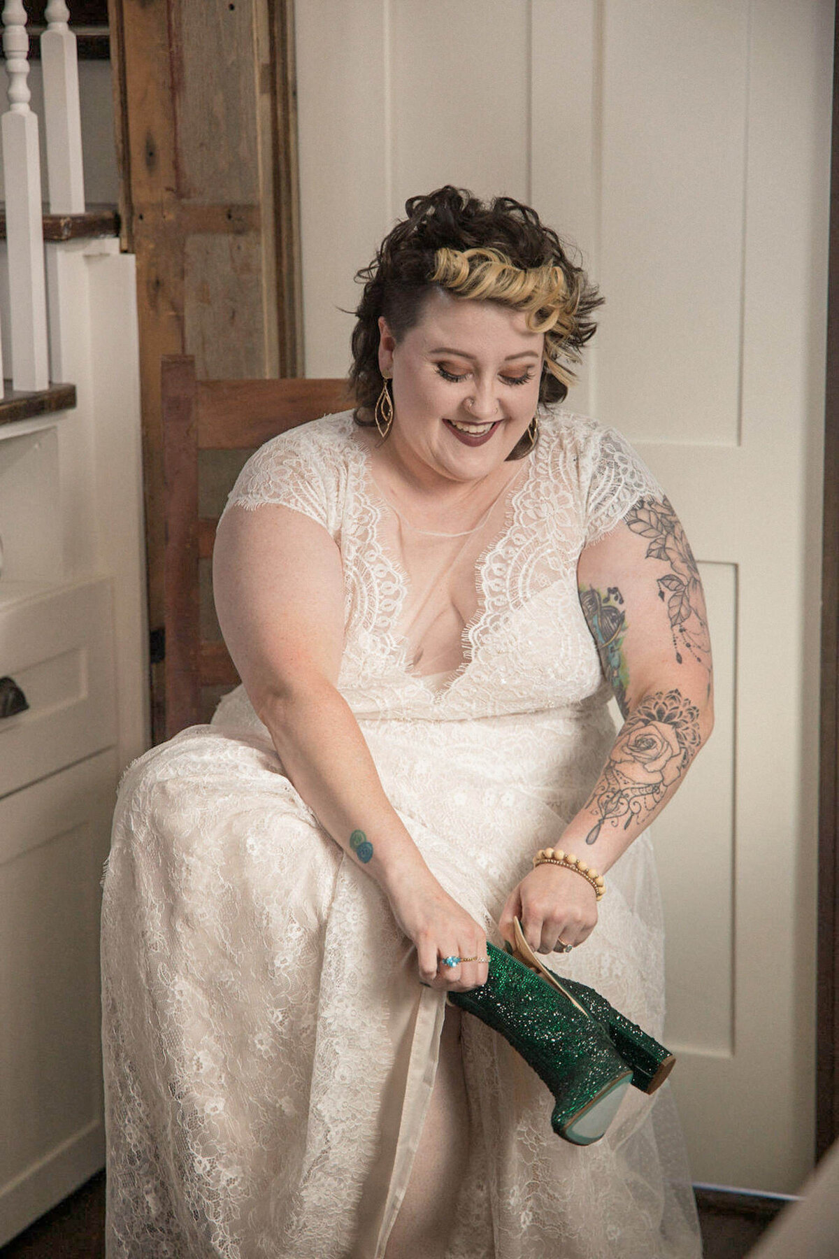 The bride,  getting ready, pulls on her emerald green, sparkly boots