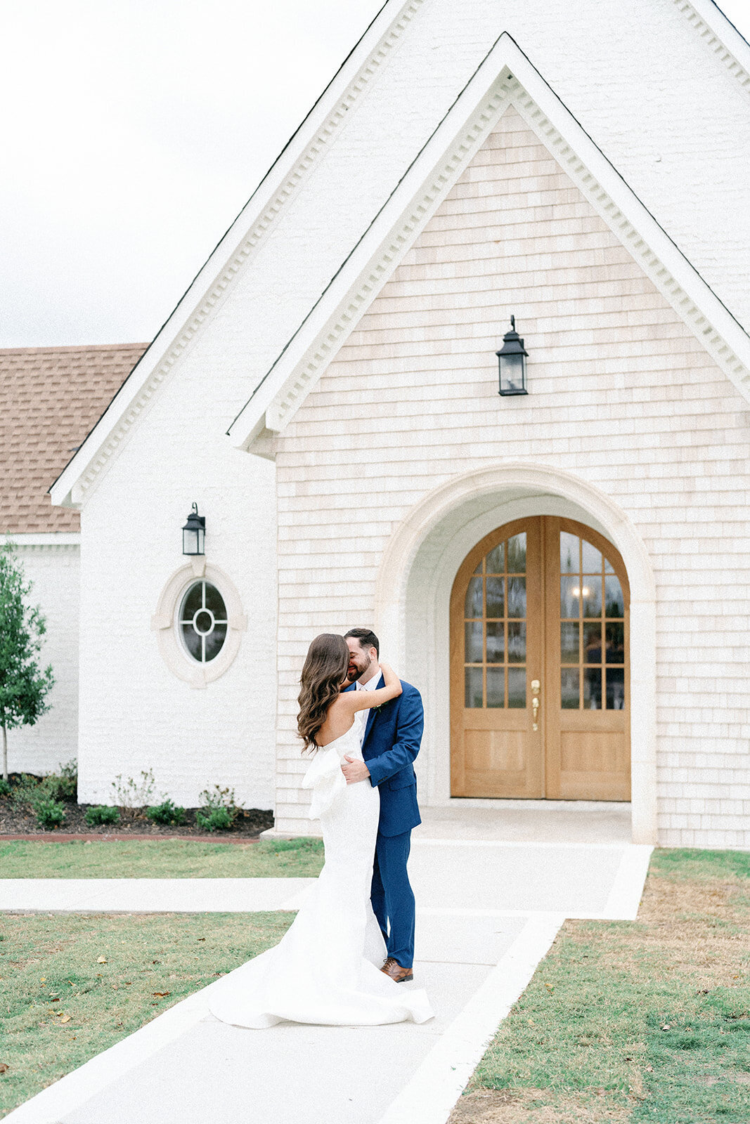 wedding couple embrace outside white wedding chapel near Dallas TX