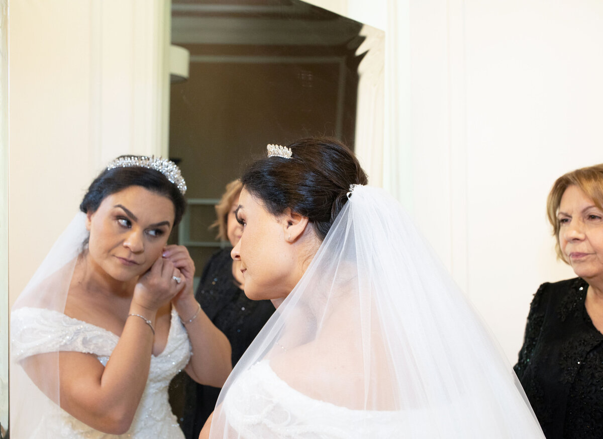 bride-putting-on-earrings-mirror-shot-callanwolde-wedding-day