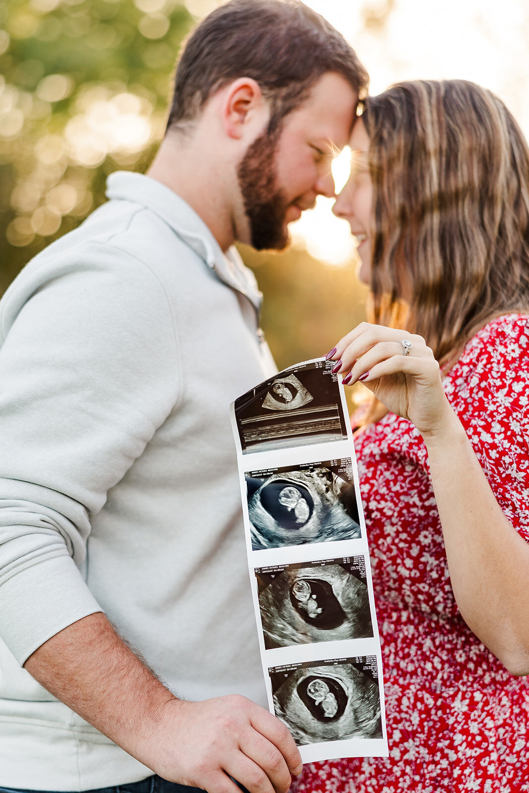 Pregnant couple standing outside holding sonogram images