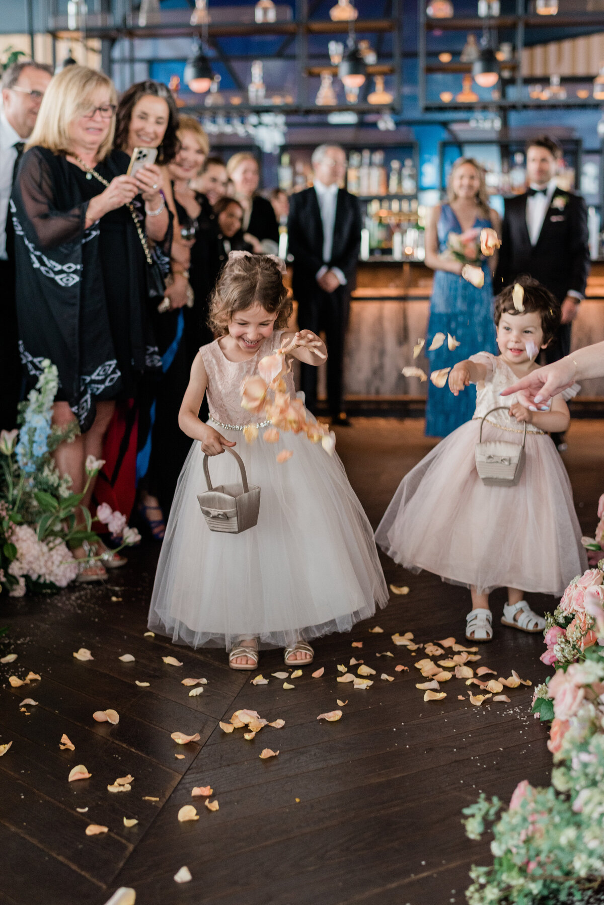 Two flower girls sprinkle petals down the alter 