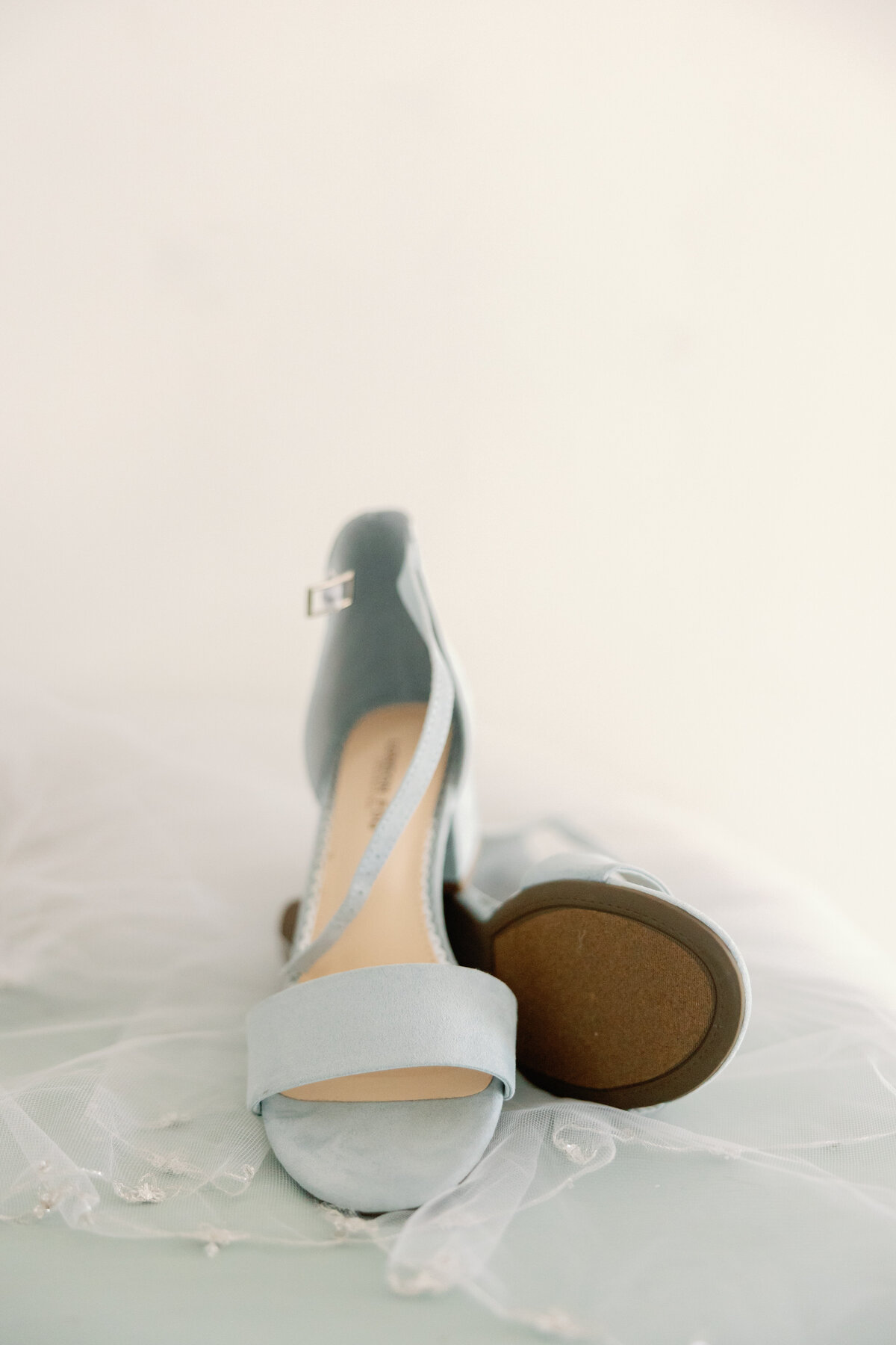 Pair of pale blue bridal shoes resting on white background.