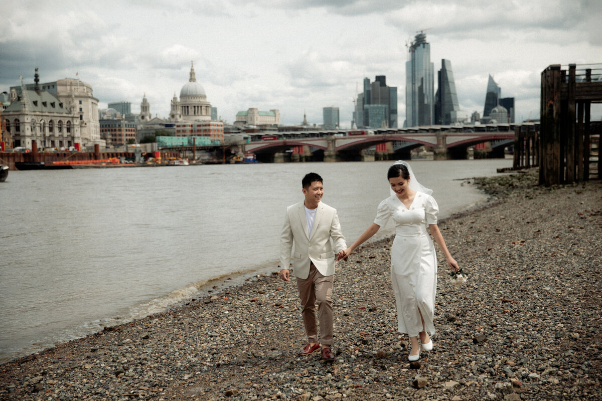 Couple eloping to London walking on the shore of River Thames with St Paul's cathedral in the background