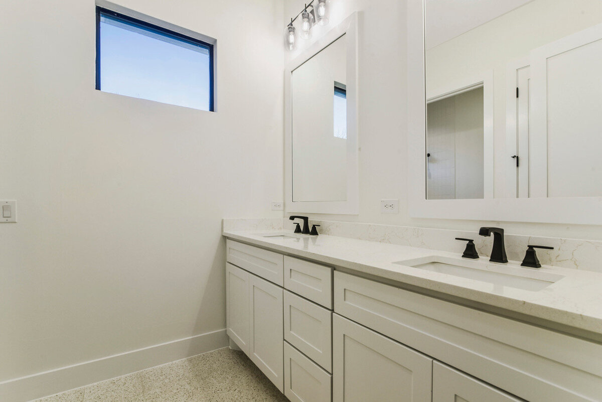 double sink vanity with shaker style cabinet doors and black faucets