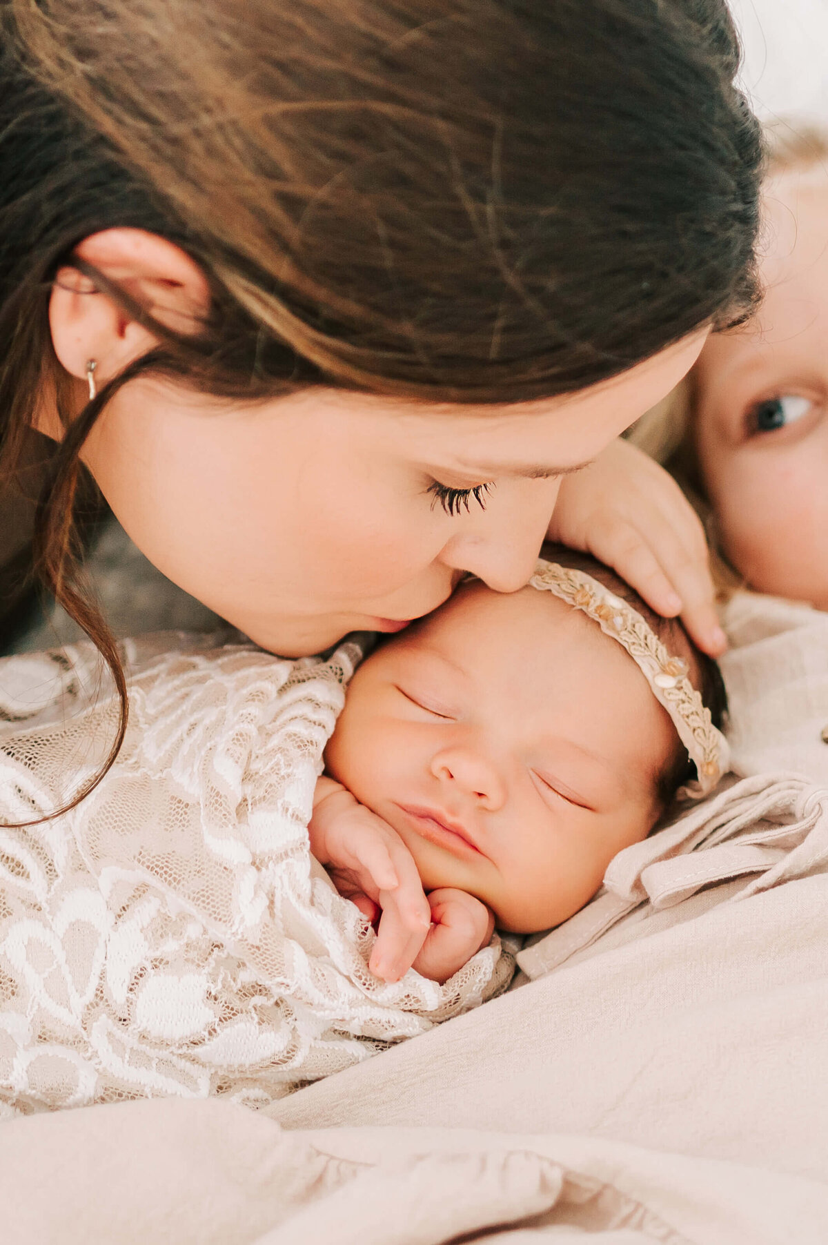 Branson Missouri newborn photographer Jessica Kennedy of The XO Photography captures mom kissing sleeping  on bed