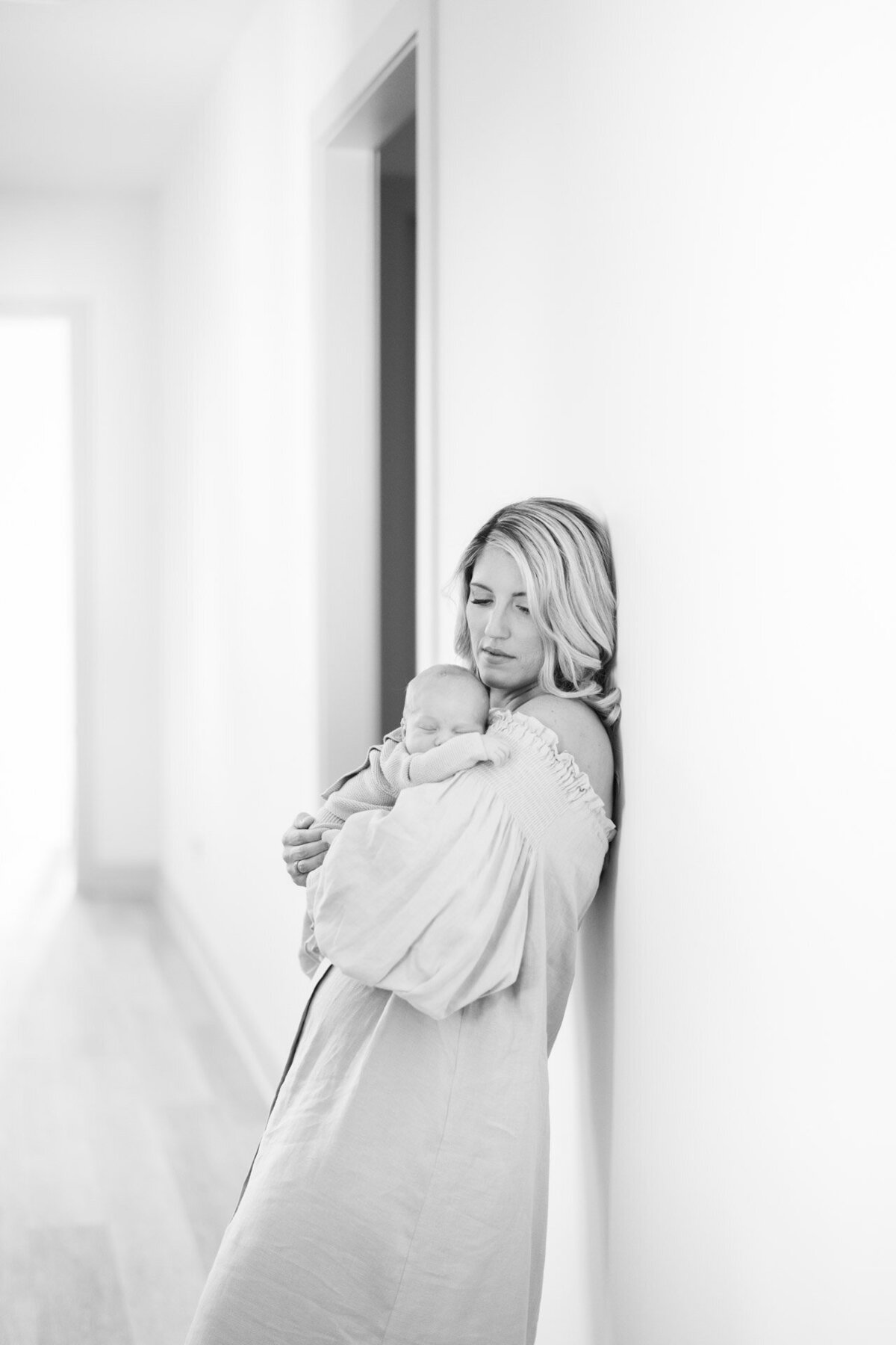 black and white photo of mom holding baby in hallway for Tampa newborn photographer Tina Marie Studio.