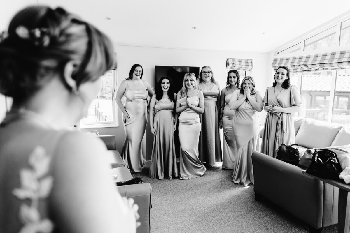 Black and white photo of Bridesmaids seeing Bride for first time in dress