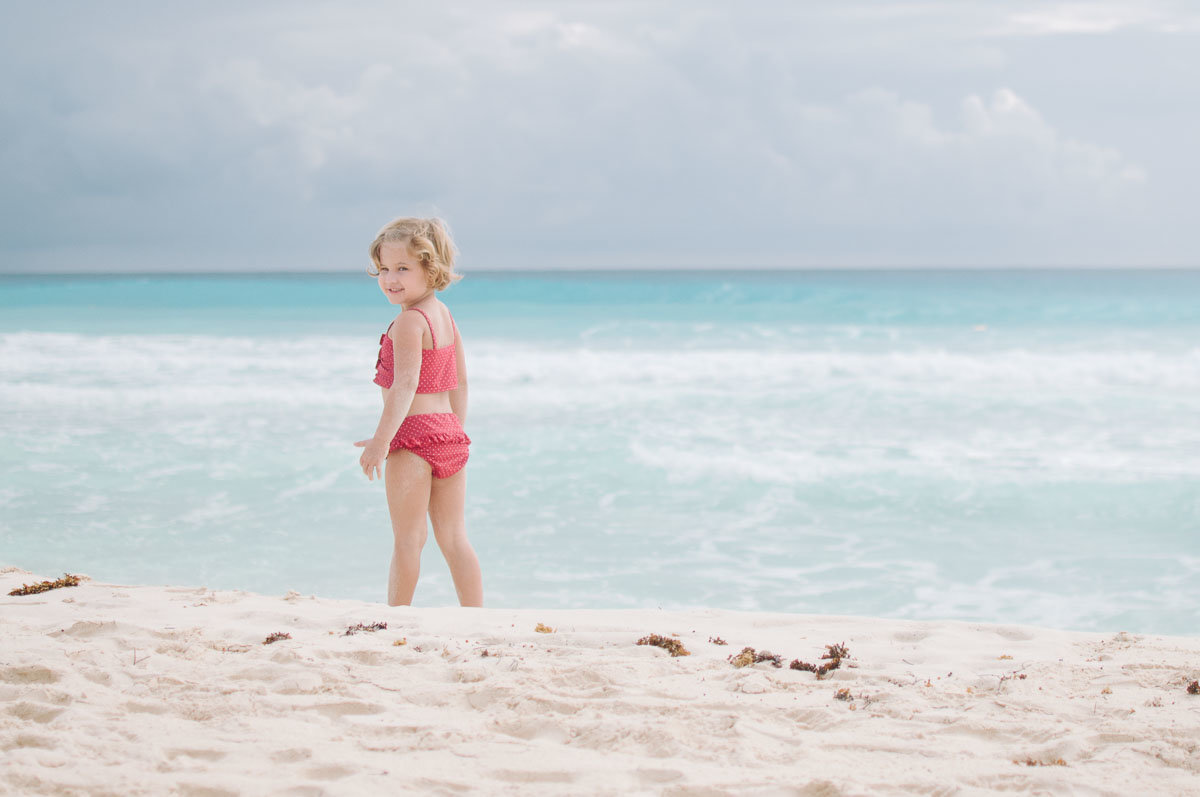 little girl in red swim suit on beach in cancun