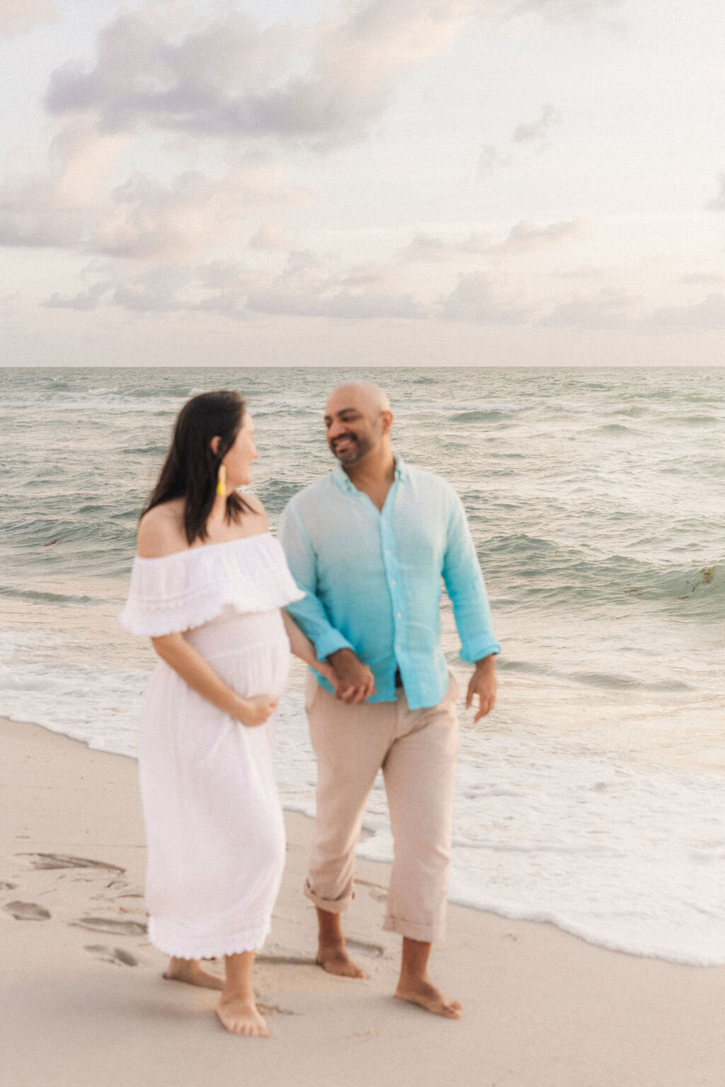 Pregnant couple walking hand in hand during a maternity session on Miami Beach, South Florida.