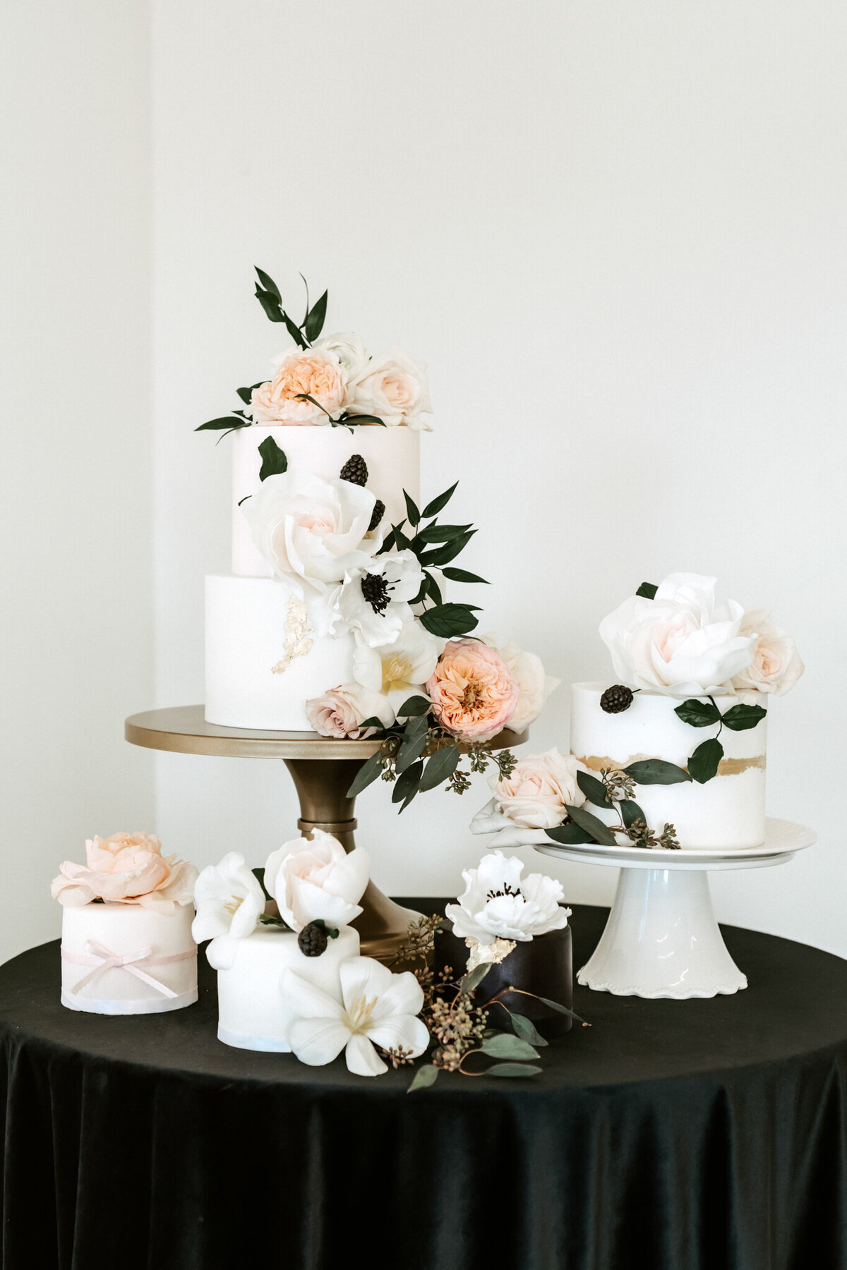 Simple and elegant white wedding cake, with gold details, pink and white florals, and greenery, by Yvonne's Delightful Cakes, classic cakes & desserts in Calgary, Alberta, featured on the Brontë Bride Vendor Guide.