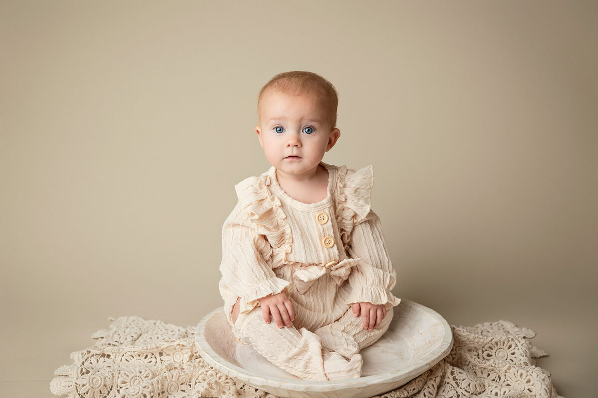 Six month old little girl posed on creamy colors for her baby session.